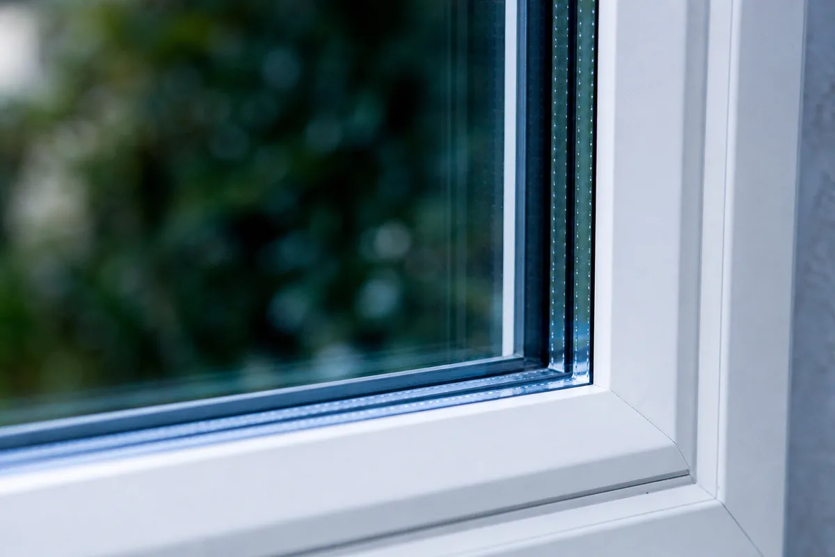 Détail d’un vitrage isolant à intercalaire, reflets froids sur le double vitrage